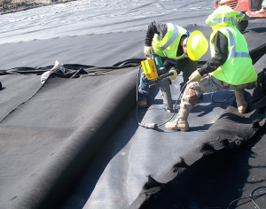 Installer repairing holes in geomembrane caused by the burning process. (CLICK IMAGE for larger view.)