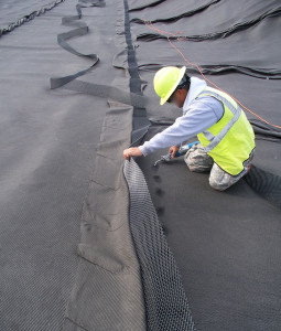 Burning holes with a propane torch without lifting the bottom sheet off the geomembrane. (CLICK IMAGE for larger view.)